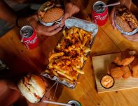 Delicious fast food spread featuring burgers, fries, nuggets, and drinks on a wooden table.